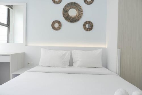a white bedroom with a bed and two mirrors on the wall at Nice and Elegant Studio at Transpark Cibubur Apartment By Travellio in Depok
