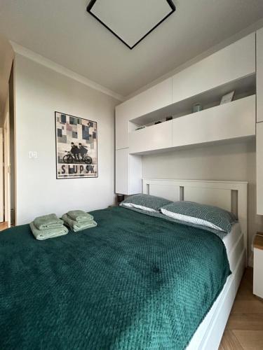 a bedroom with a large bed with a green bedspread at Witkacy Apartament in Słupsk