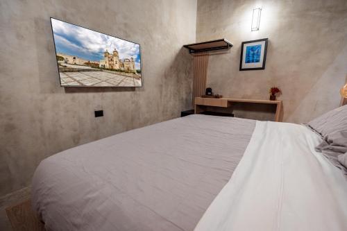 a bedroom with a white bed and a picture on the wall at Casa 1800 Oaxaca Boutique Hotel City Center based in Oaxaca City