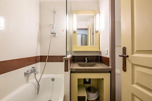 une salle de bain avec un lavabo, une baignoire et un miroir dans l'établissement Résidence le Village de Cap Esterel - maeva Home - Studio 4 personnes - Sélection MAE-2641, à Saint-Raphaël