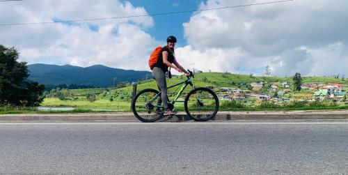 a man riding a bike down a road at Gregory House Hostel in Nuwara Eliya