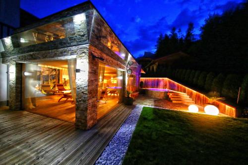 a house with a wooden deck at night at La Bercia Alpine Lodge & Spa in La Villa