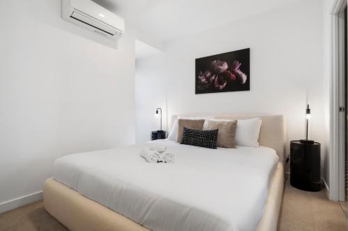 a white bedroom with a large white bed at Stylish and Spacious 2BR w Study, Wi-Fi and Car Park in Carnegie