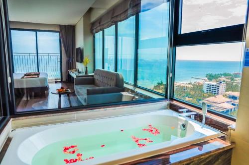 a bath tub in a room with a large window at Vipol Mui Ne Hotel & Spa in Mui Ne