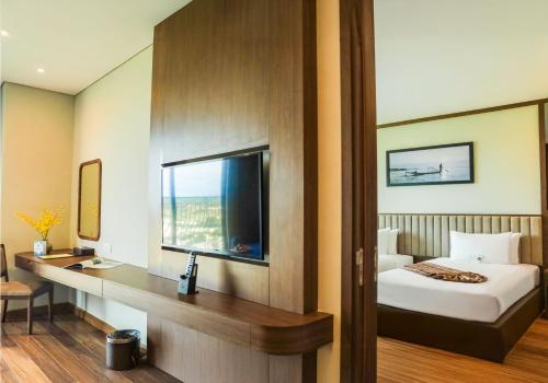 a bedroom with a bed and a desk and a window at Vipol Mui Ne Hotel & Spa in Mui Ne