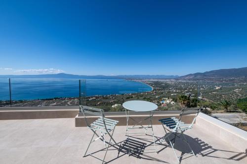 a table and chairs on a balcony with a view of the ocean at Cella Villa in Kalamata
