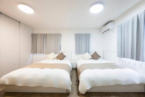 two beds in a room with white walls and windows at AMP FLAT Hontosu in Tashiro