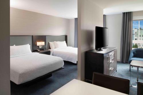 a hotel room with two beds and a flat screen tv at Homewood Suites By Hilton Boston Logan Airport Chelsea in Chelsea