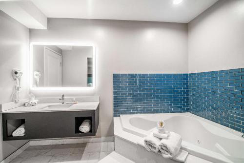 a bathroom with a tub and a sink and a mirror at Rodeway Inn South Gate - Los Angeles South in South Gate