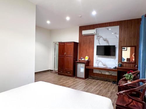 a bedroom with a bed and a desk and a television at Brenta Phu Quoc Hotel in Phu Quoc