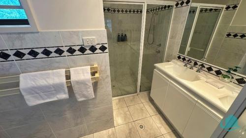 un baño con lavabo y ducha en Azure Vista, en Belmont
