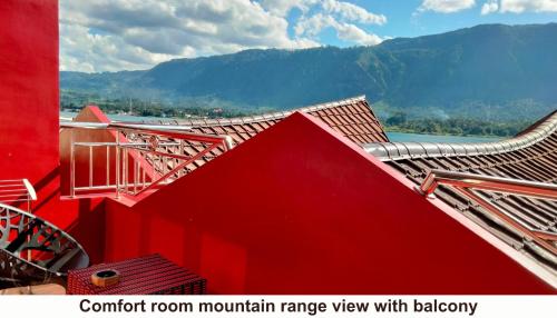 a red building with a red mountain range in the background at Zoé’s Paradise Waterfront Hotel in Tuk Tuk