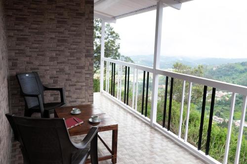 a room with a balcony with a table and chairs at Heath Cote in Ooty