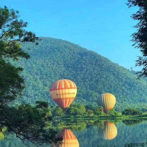 three hot air balloons flying over a body of water at Sigiri Rangana Guesthouse in Sigiriya