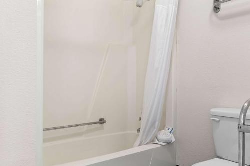 a bathroom with a tub and a toilet with a shower curtain at Rodeway Inn & Suites Saginaw I-675 in Saginaw