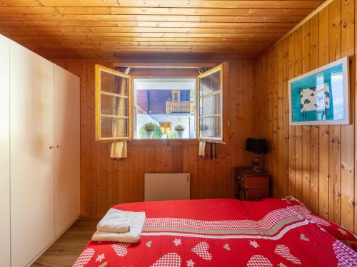 a bedroom with a red bed and two windows at Chalet Verrel near Aletsch Ski Gondolas in Fiesch