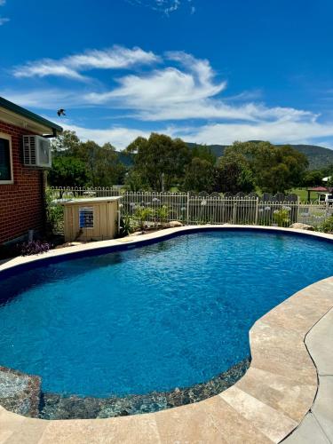 a swimming pool with blue water in front of a house at Roseville Motel and Apartments in Tamworth