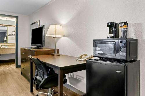 a room with a desk with a television and a microwave at Rodeway Inn & Suites Saginaw I-675 in Saginaw