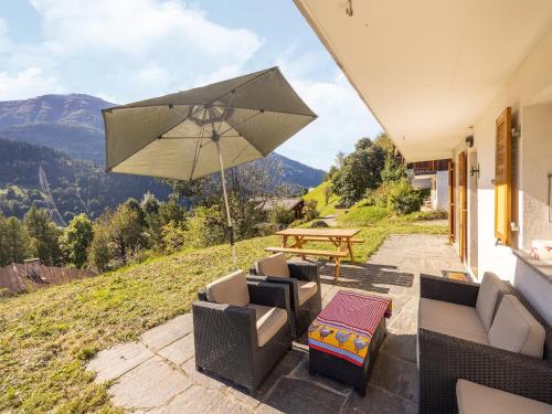 a patio with a table and chairs and an umbrella at Chalet Verrel near Aletsch Ski Gondolas in Fiesch