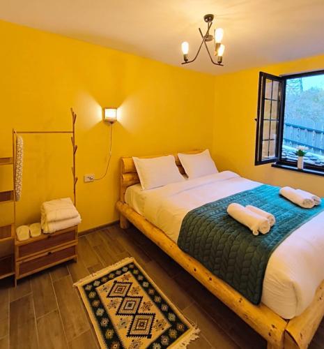 a bedroom with a large bed with yellow walls at Woodlandia Resort Borjomi in Borjomi