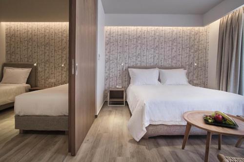 a bedroom with two beds and a table with a bowl of fruit at Utopia Blu Hotel in Tigaki
