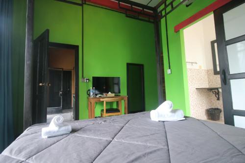 a green room with a bed with two white towels on it at Bat Chum Villa in Phnom Penh