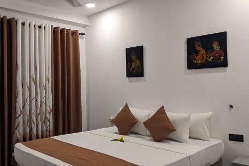 a bedroom with a bed with two pictures on the wall at Mayon Beach villa in Tangalle