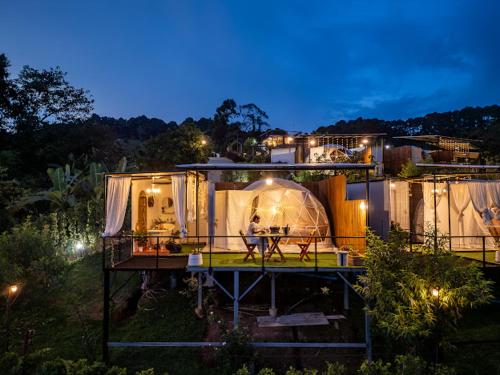 a house with a tent in the yard at night at Phu Morinn Cafe &Camping Monjam in Mon Jam