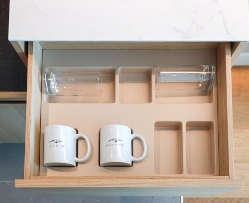 two mugs in a drawer of a kitchen cabinet at Haenam 126 Hotel in Haenam