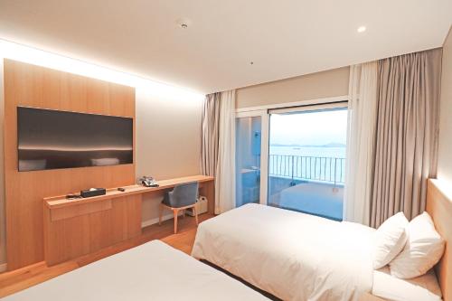 a hotel room with a bed and a desk and a window at Haenam 126 Hotel in Haenam