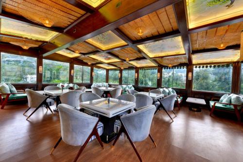a restaurant with tables and chairs in a room with windows at Chacha Inn The Garden Retreat in Mount Ābu