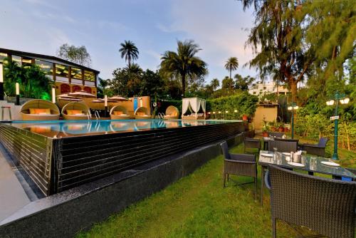 a resort with a swimming pool with tables and chairs at Chacha Inn The Garden Retreat in Mount Ābu