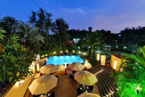 a view of a pool with umbrellas at night at Chacha Inn The Garden Retreat in Mount Ābu
