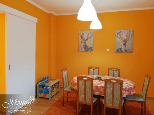 a dining room with orange walls and a table and chairs at Jázmin Apartmanház in Szentgotthárd