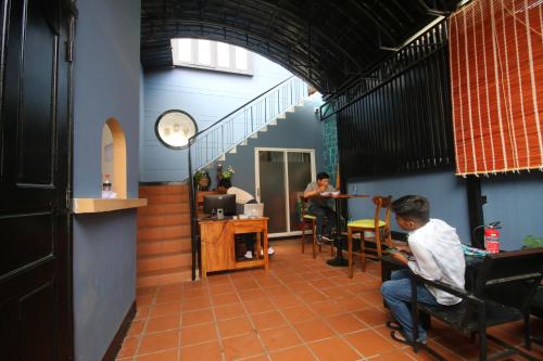 two men sitting at tables in a room with a staircase at Bat Chum Villa in Phnom Penh