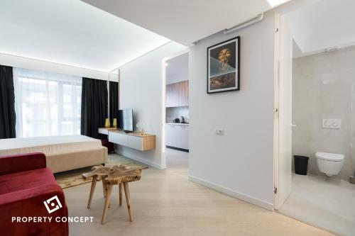 a white bedroom with a bed and a red couch at Cortina Concept Studio 128 in Voluntari