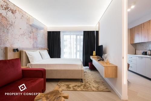 a hotel room with a bed and a red chair at Cortina Concept Studio 128 in Voluntari