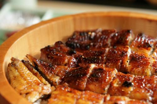 a wooden plate of food with meat and sauce at Hotel Green Plaza Hamanako in Hamamatsu