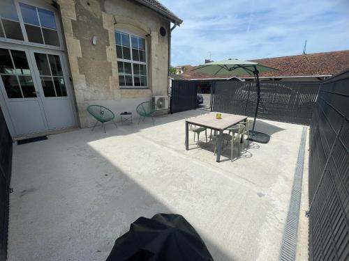 a patio with a table and an umbrella at Le Côté Cour in Dole