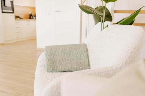 a white chair with a pillow on it in a living room at Küsten Suite Grachten Suite 2 direkte Wasserlage, Terrasse, 76qm, Neubaugebiet in Greetsiel
