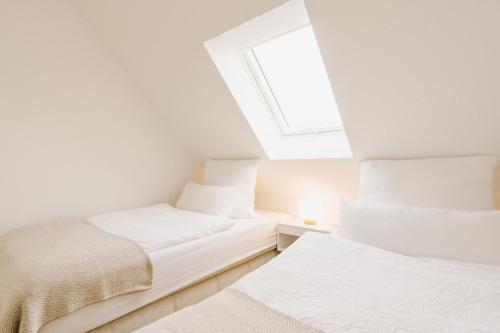 two beds in a white room with a window at Küsten Suite Grachten Suite 2 direkte Wasserlage, Terrasse, 76qm, Neubaugebiet in Greetsiel
