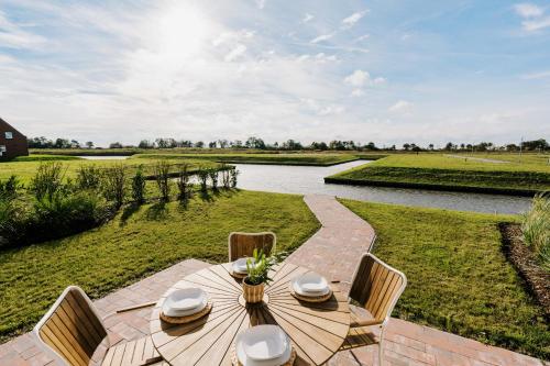a wooden table with chairs and a view of a river at Küsten Suite Grachten Suite 2 direkte Wasserlage, Terrasse, 76qm, Neubaugebiet in Greetsiel