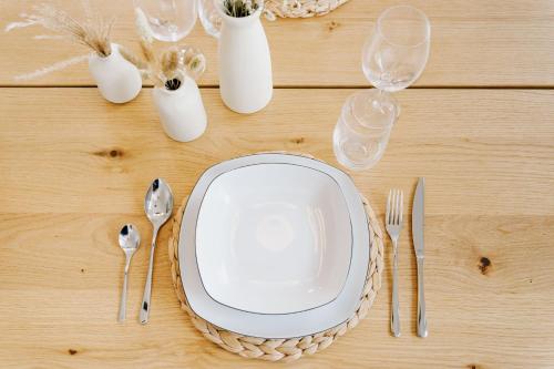 a table with a plate and cutlery on it at Küsten Suite Grachten Suite 2 direkte Wasserlage, Terrasse, 76qm, Neubaugebiet in Greetsiel