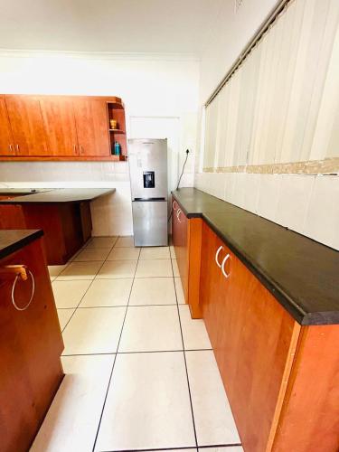 a kitchen with wooden cabinets and a stainless steel refrigerator at Executive Accommodation Bellville 2 in Cape Town