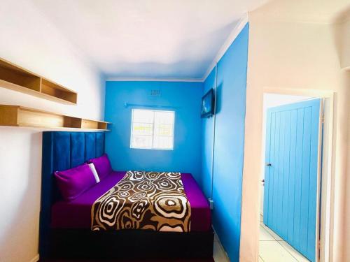a blue bedroom with a bed with purple sheets at Executive Accommodation Bellville 2 in Cape Town