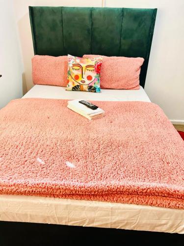 a bed with a pink blanket and a remote control on it at Executive Accommodation Bellville 2 in Cape Town