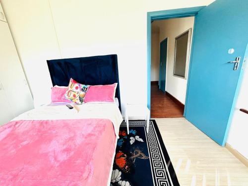 a bedroom with a bed with pink sheets and a blue door at Executive Accommodation Bellville 2 in Cape Town