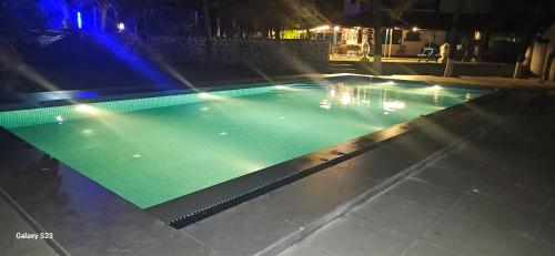 an empty swimming pool at night with lights at Aqua Arina Holiday Farm House in Murud