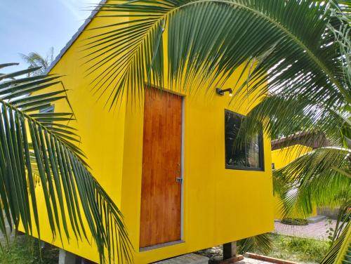 a yellow house with a wooden door and a palm tree at BONNIE HOMESTAY Mui Ne in Mui Ne