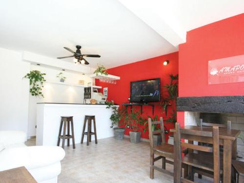 una sala de estar con una pared roja y un bar. en San Remo Amapola Apart Hotel en Ostende